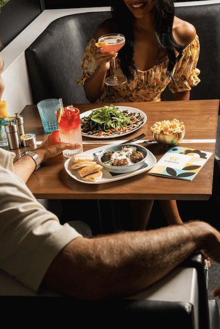 Friends enjoying cocktails, small plates, and vibrant atmosphere during Worthwyld Happy Hour in Miami.”
